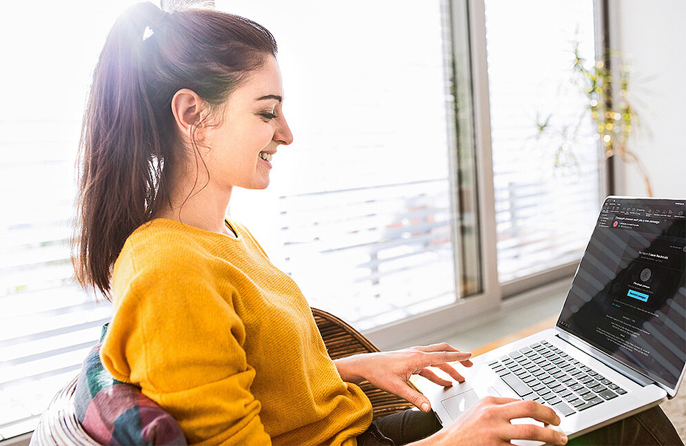 Una mujer feliz con un portátil en el regazo